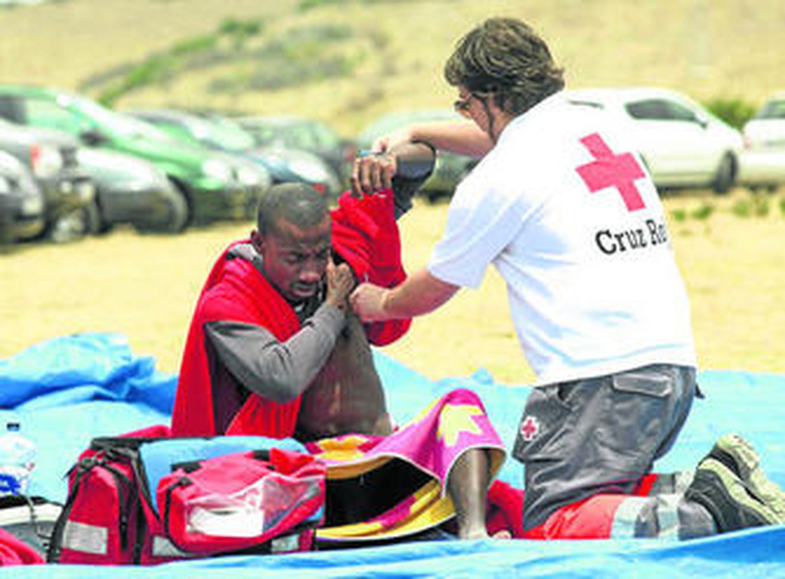 Un miembro de la Cruz Roja atiende a un inmigrante ayer en la playa de Bolonia, en Tarifa.