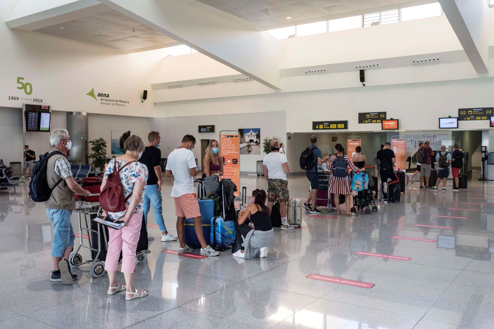Viajeros hacen cola para facturar en el aeropuerto de Mahón, en Menorca.