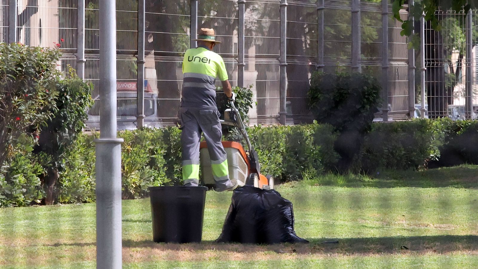 Un trabajador corta el césped de una zona ajardinada.