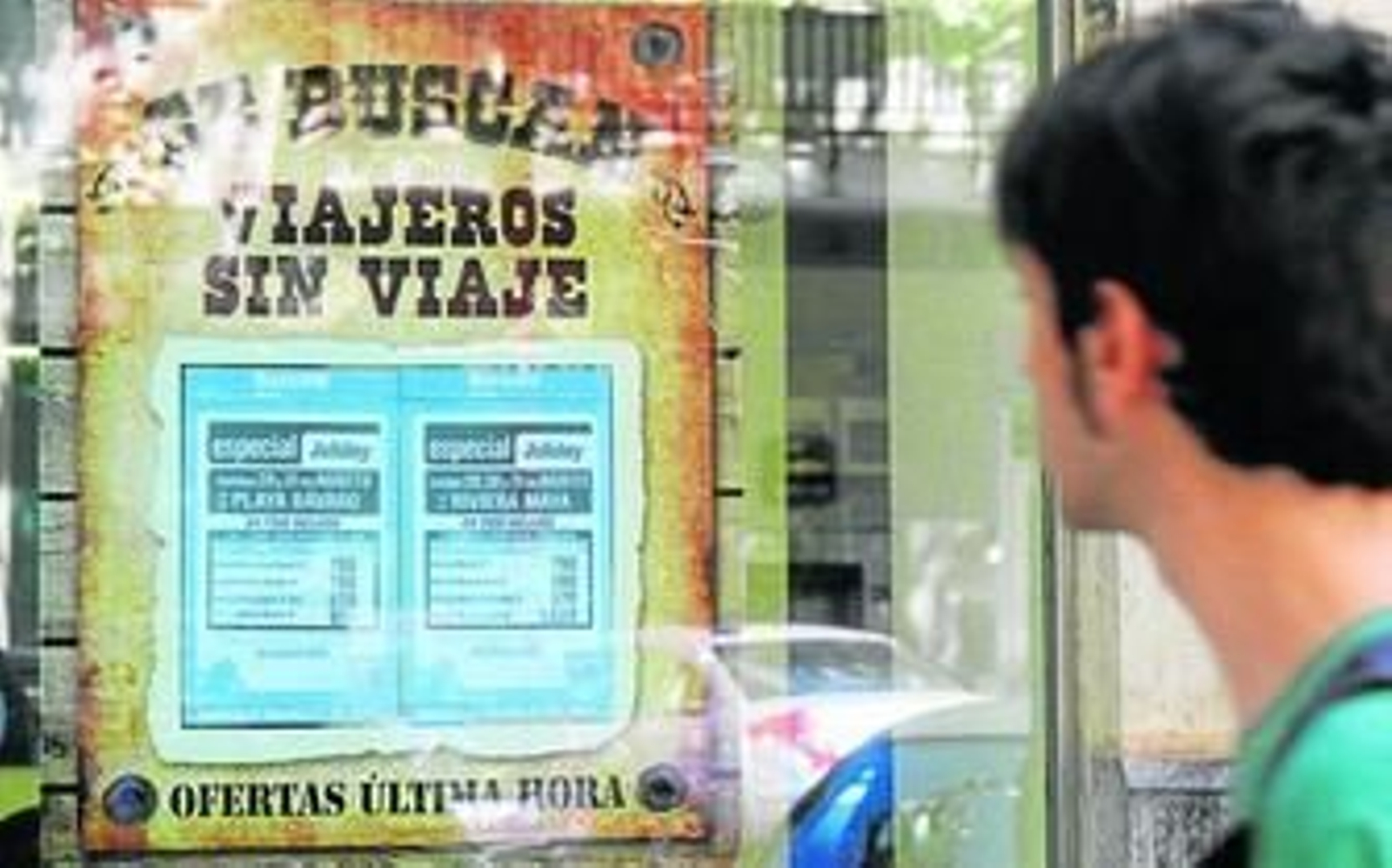 Un joven observa las ofertas expuestas en el escaparate de una agencia de viajes tradicional.