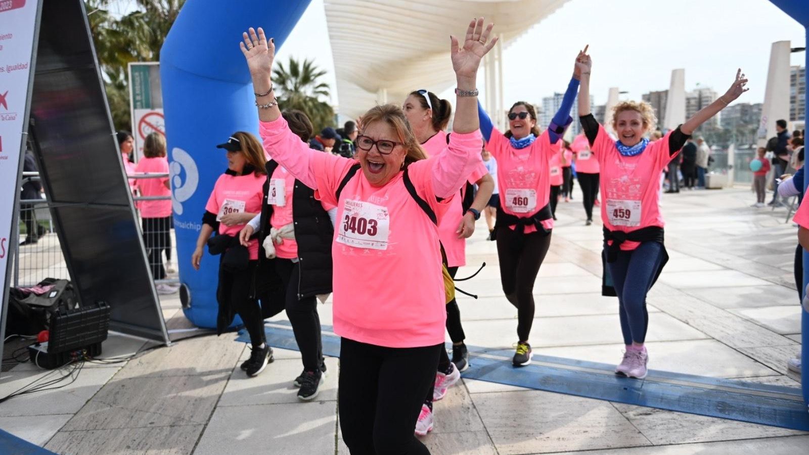 Varias participantes celebran su llegada a la meta en la Carrera de la Mujer contra el Cáncer en Málaga