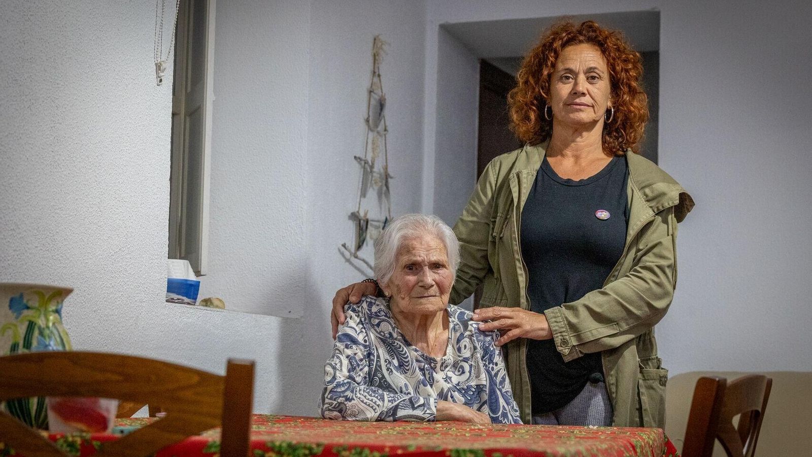 María Muñoz, con su hija, Eva Orihuela, en la salita de su casa en el barrio de El Pópulo.