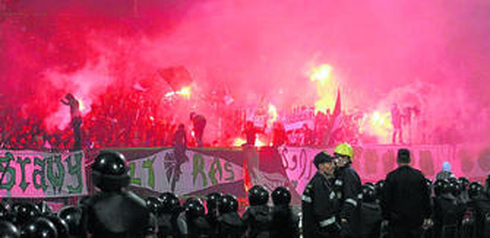 Los seguidores del Al Masri encienden bengalas durante el partido ante la atenta mirada de la policía.