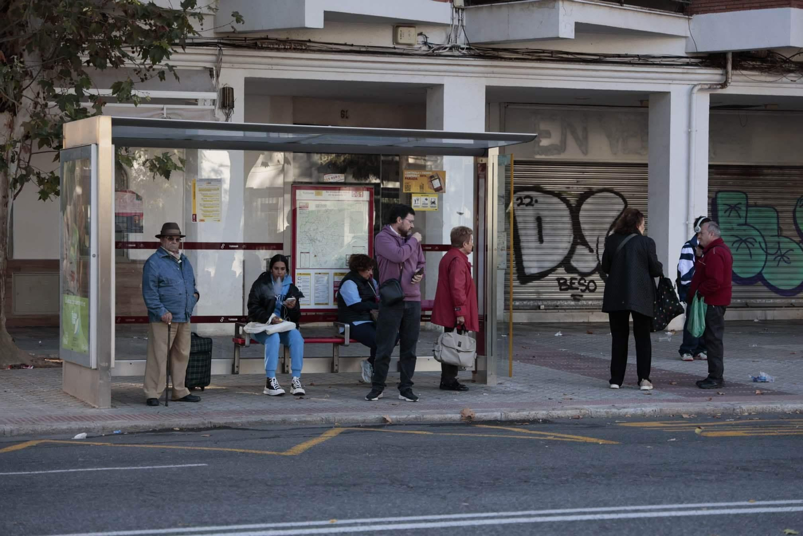 Varias personas esperan en una parada de Tussam