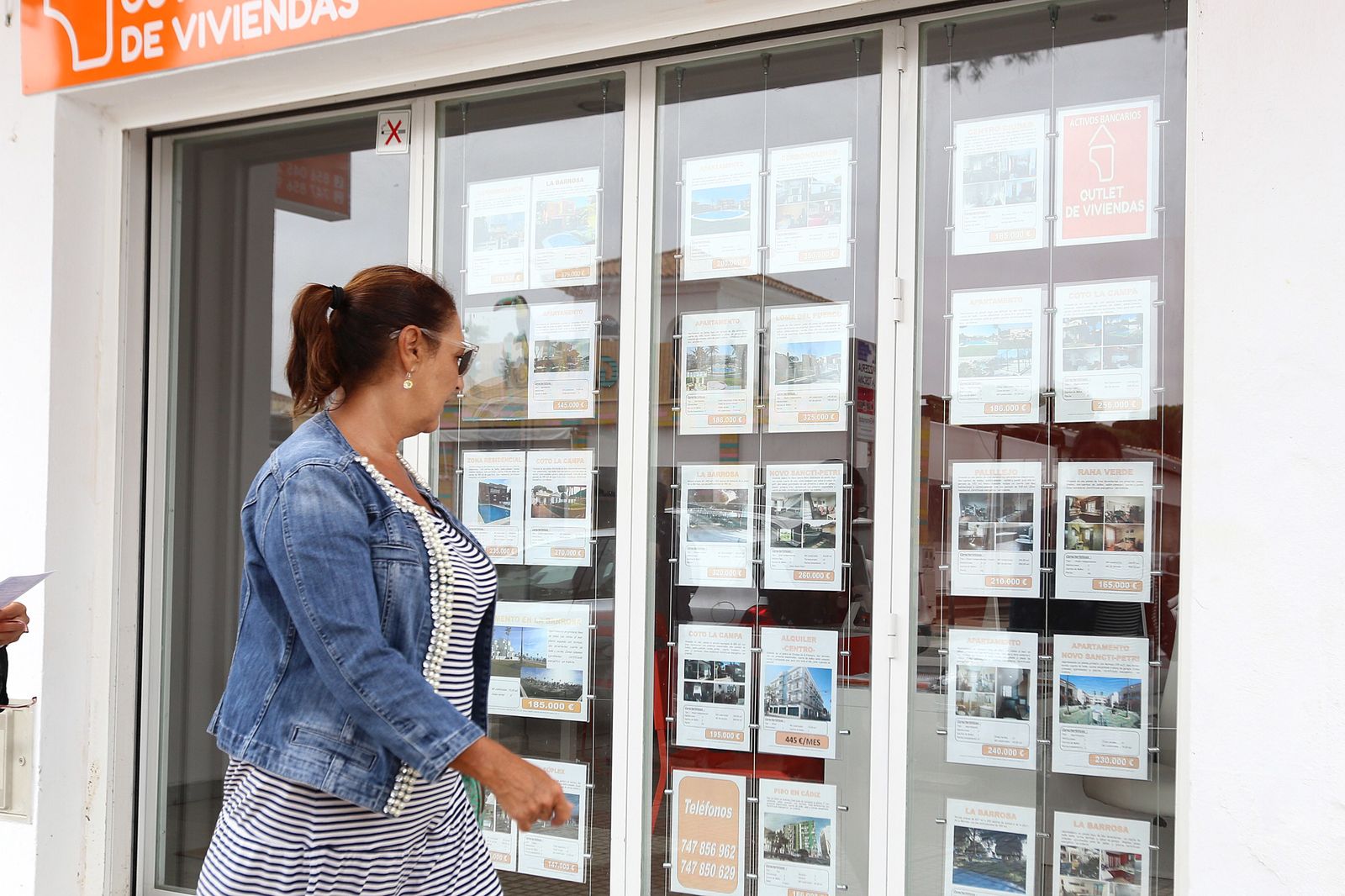 Una mujer pasa ante una inmobiliaria en Chiclana.