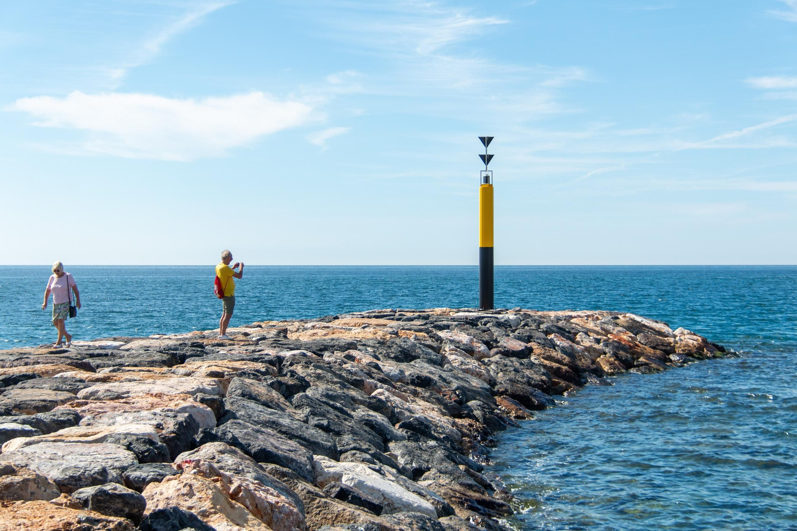Dos personas en la parte final del espigón de Playa Granada, haciendo una foto Dos personas en la parte final del espigón de Playa Granada, haciendo una foto
