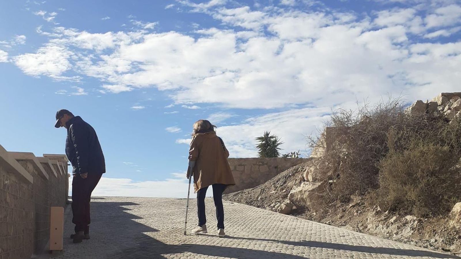 Una mujer asciende con dificultad la cuesta mientras un señor observa uno de los focos destrozado