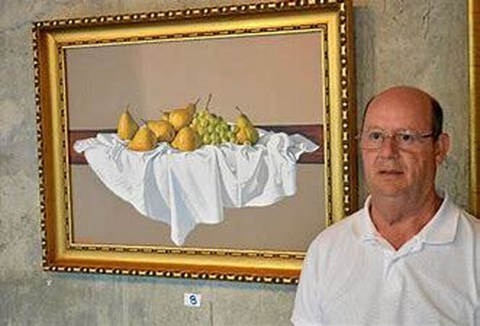 Lázaro Perdigones Cruzado junto con uno de sus cuadros.