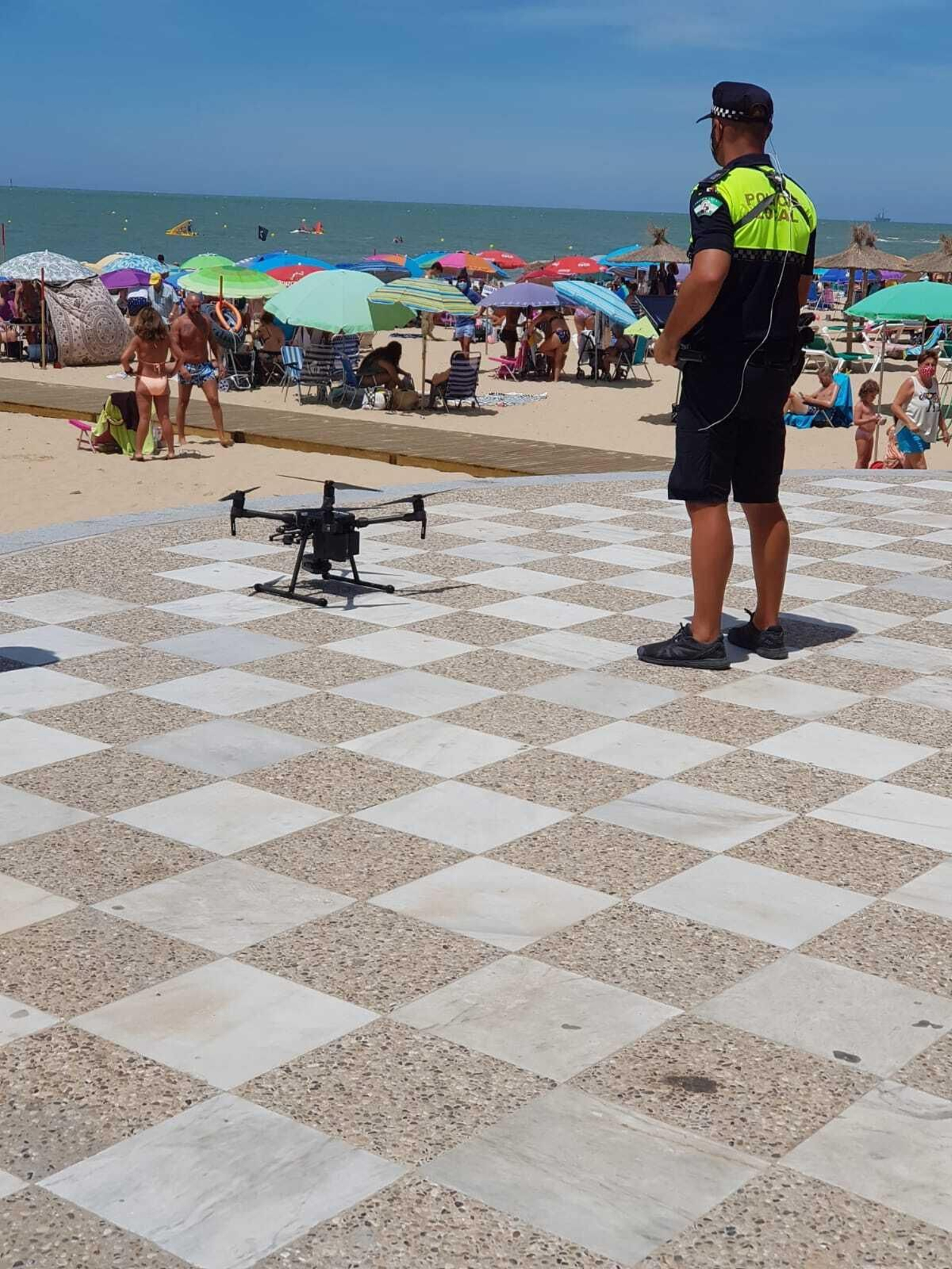 Un agente de la Policía Local de Chipiona pilota uno de los drones para controlar el aforo.