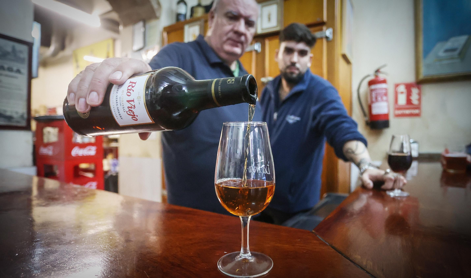 Un hostelero sirve una copa de jerez en un bar del centro.