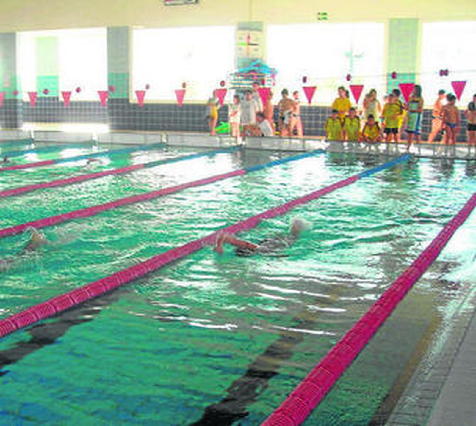 Niños disfrutan de las clases de natación en la piscina.