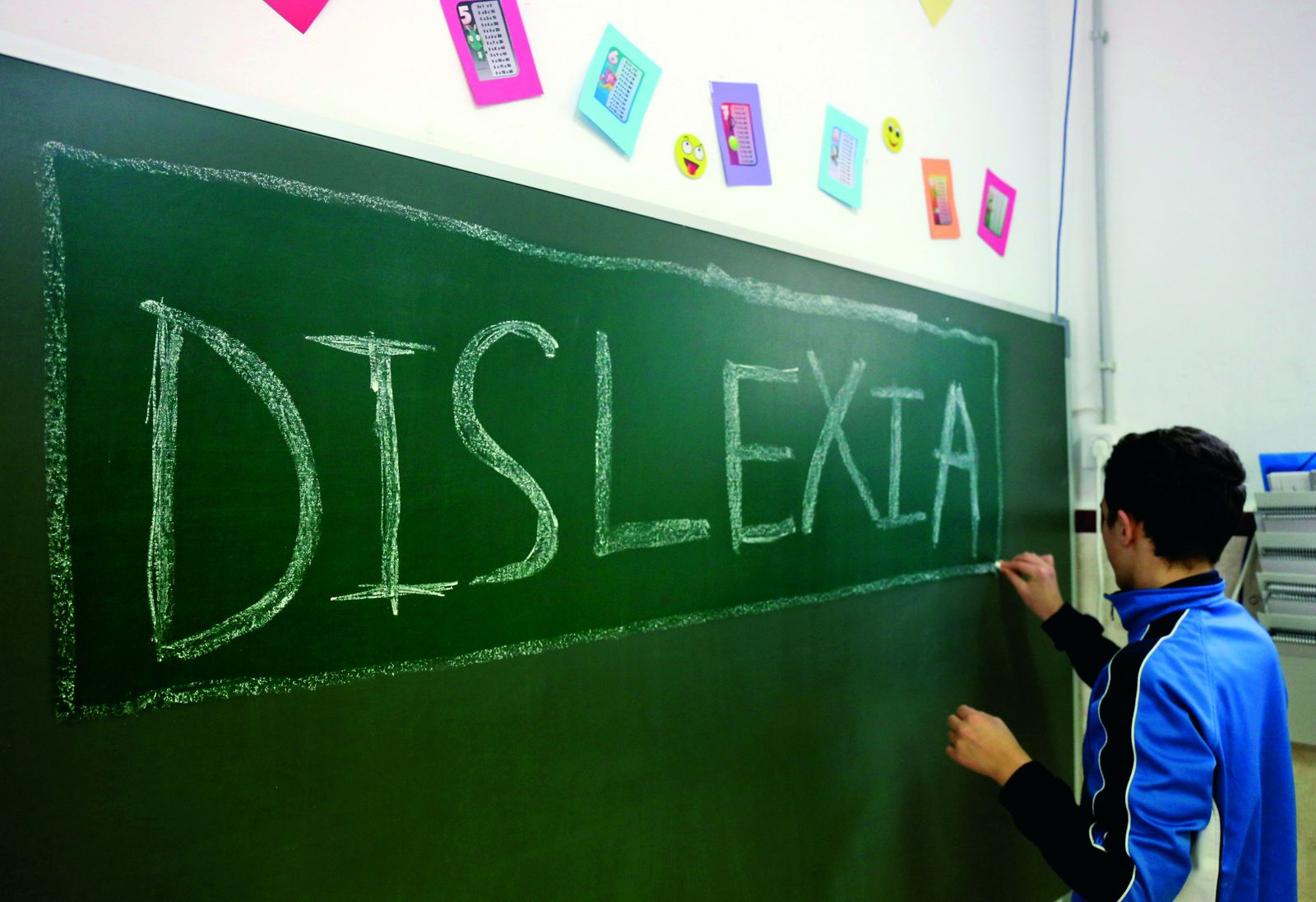 Un alumno escribe en la pizarra la palabra dislexia.