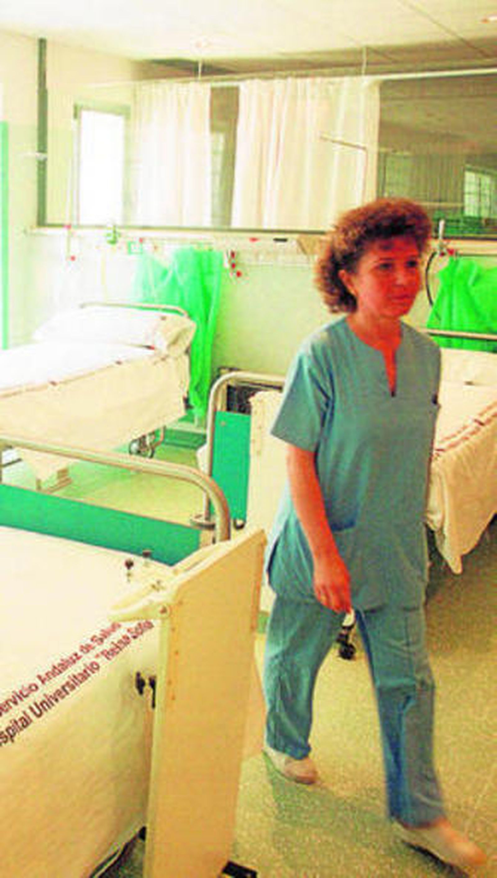 Una enfermera en una sala llena de camas hospitalarias.