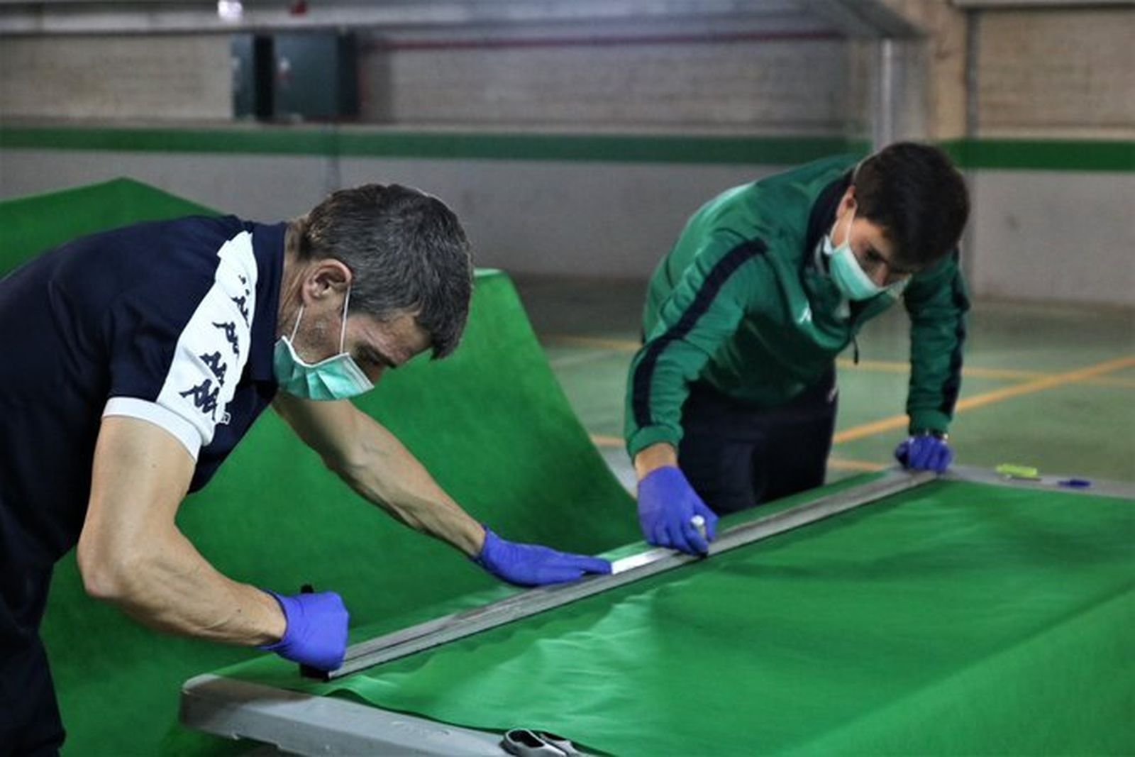 Volluntarios béticos confeccionan las batas.