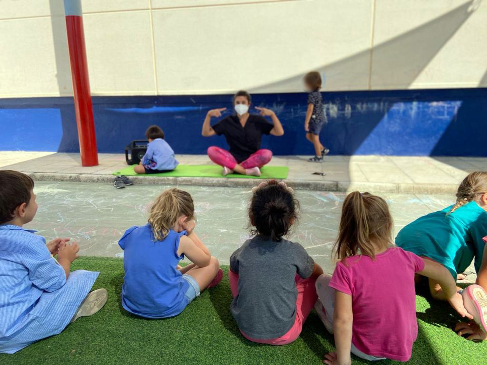 Una docente con mascarilla en una clase.