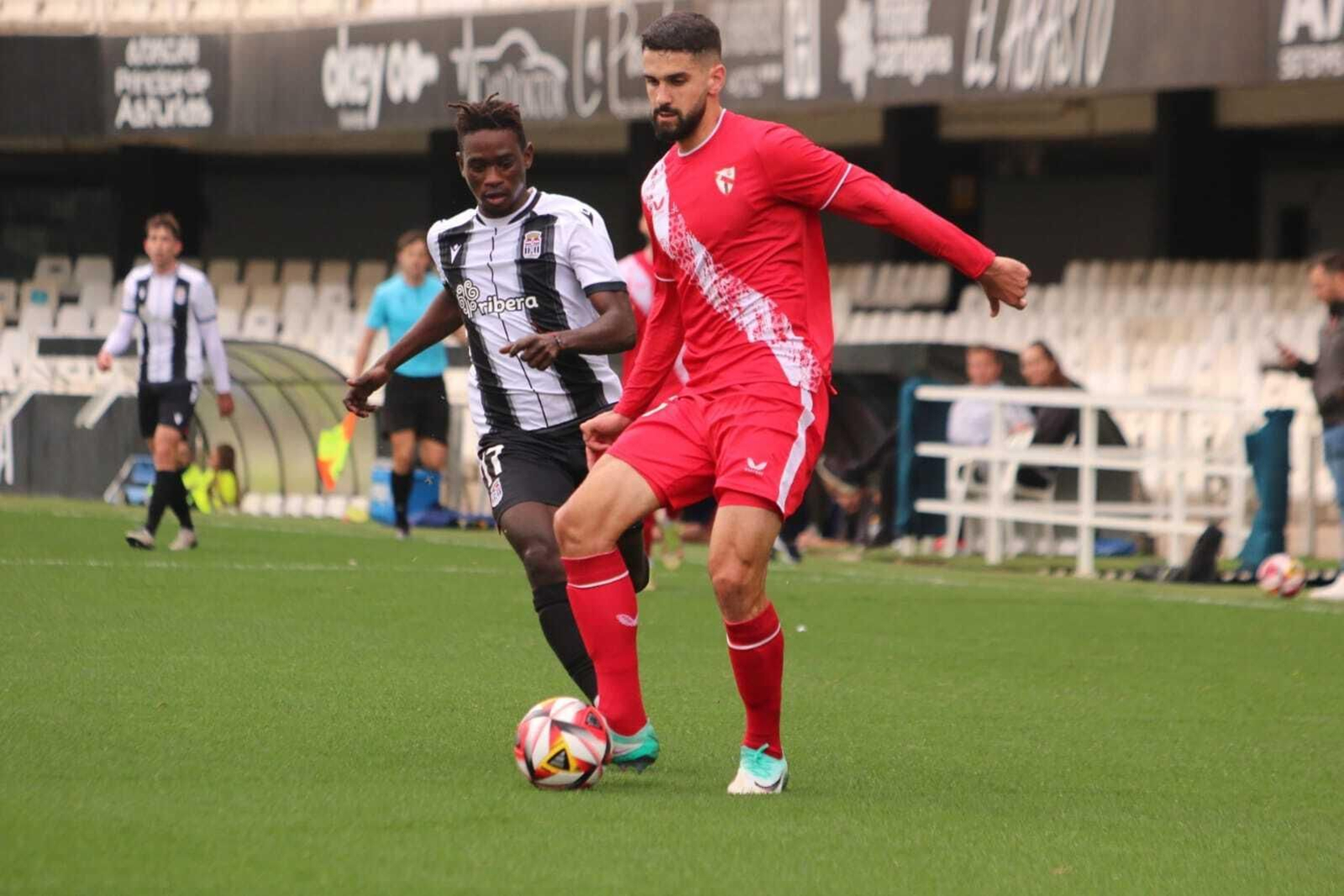 Xavi Sintes cede atrás ante la presión de Djaka en el Cartagena B-Sevilla Atlético.