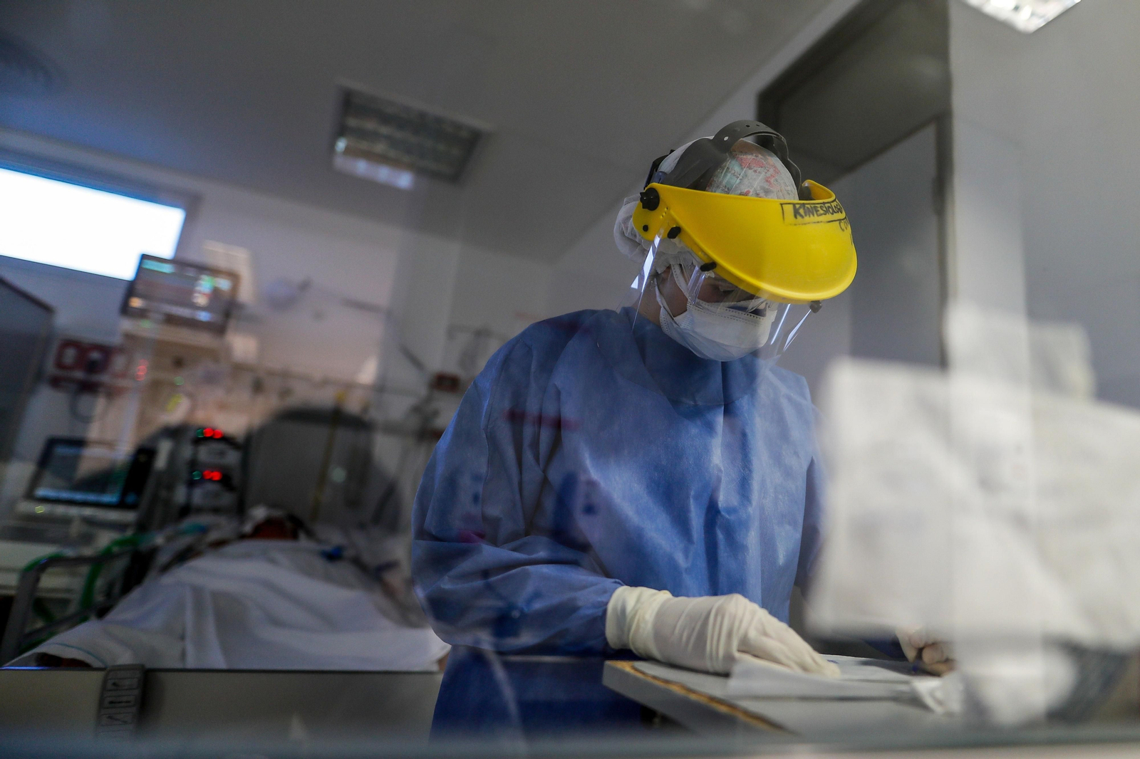 Una médica comprueba el historial clínico de un paciente protegida con un EPI. Una médica comprueba el historial clínico de un paciente protegida con un EPI.