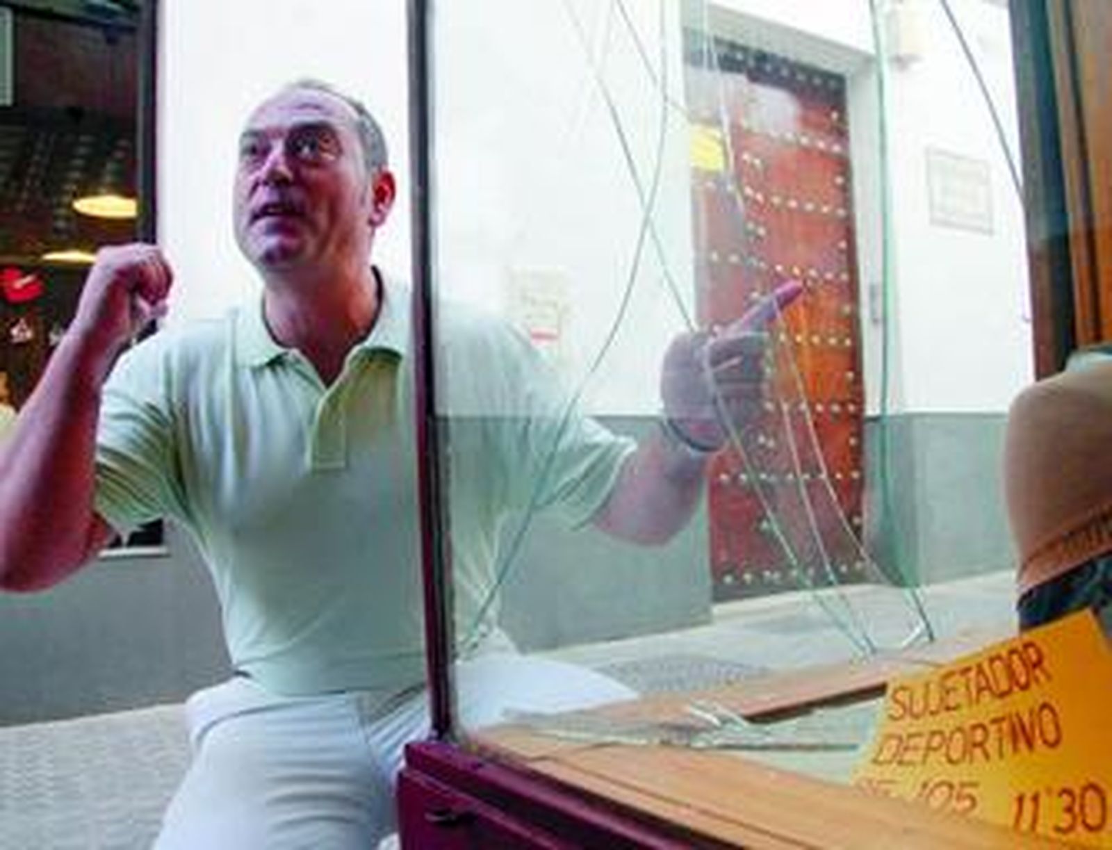 Rafael del Castillo señala la rotura del escaparate que los vándalos realizaron en su tienda.