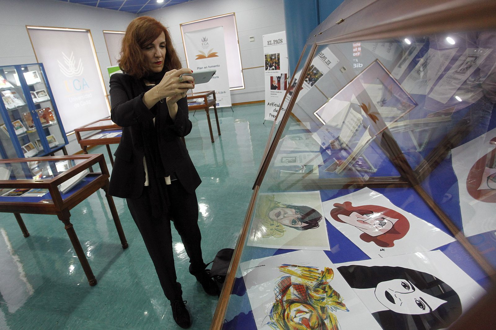 Elvira Lindo fotografía con su móvil la vitrina que muestra algunas de las caricaturas que le han dibujado.