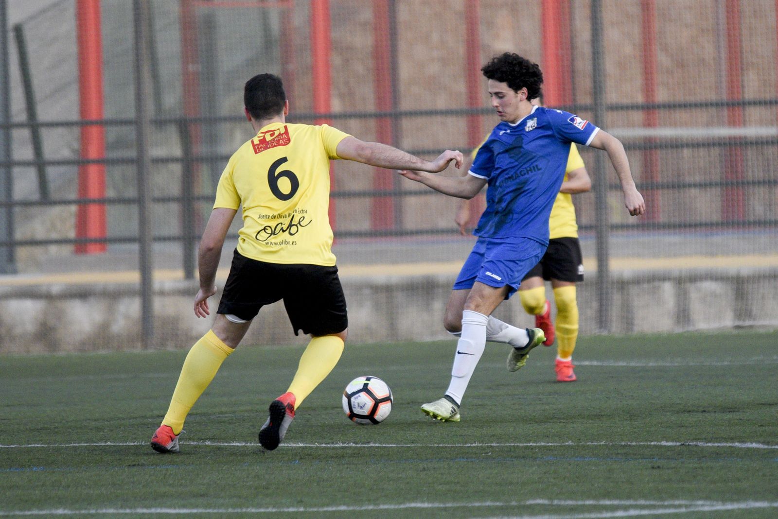 Un jugador del Monachil conduce el esférico perseguido por dos rivales.