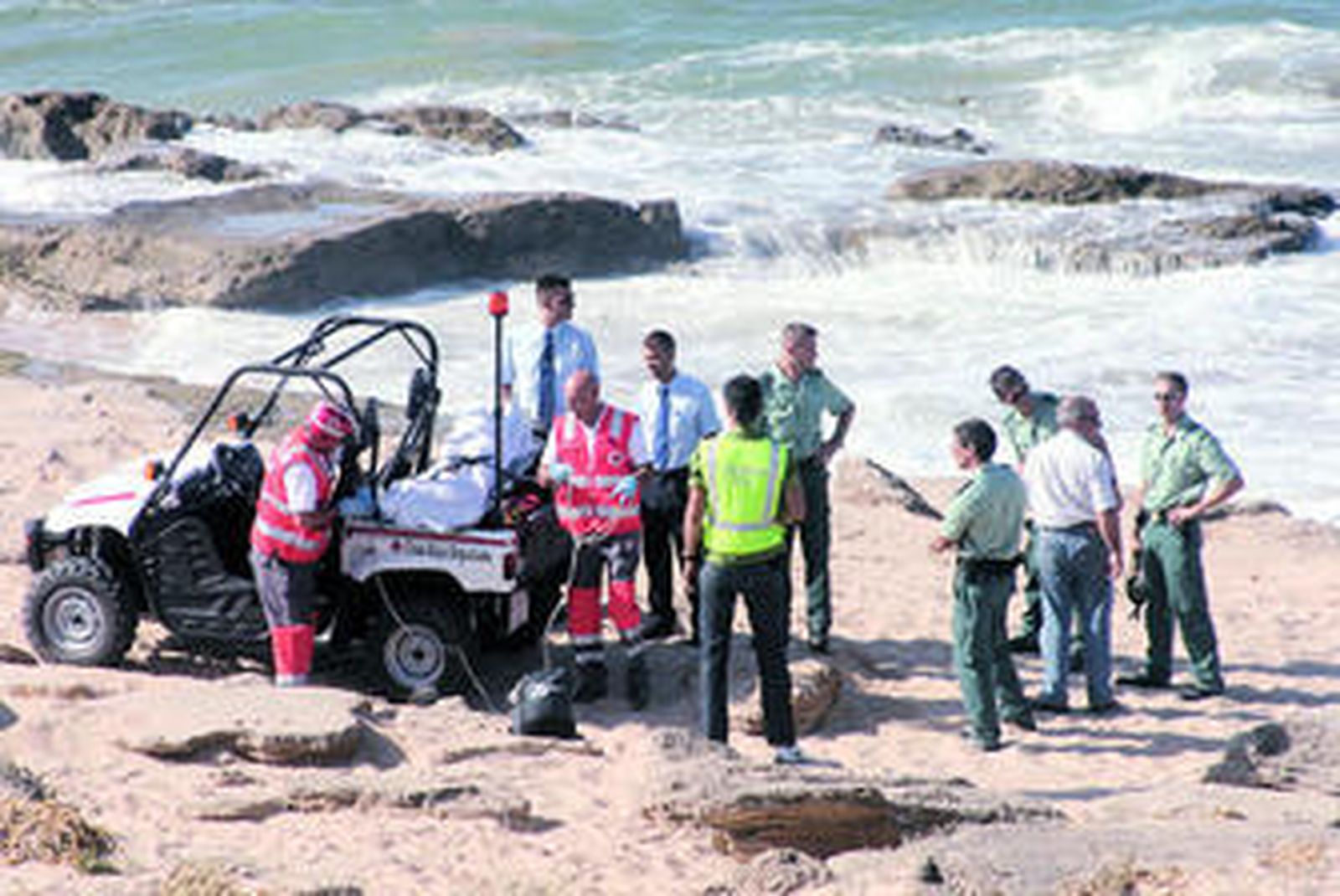 Miembros de la Cruz Roja trasladan el cadáver, ante la mirada de guardias civiles y operarios de la funeraria.