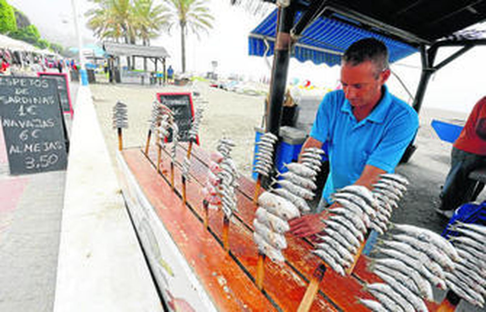1. El chiringuito Antonio, en la playa del Chanquete, uno de los que ha optado por bajar el precio a 1 euro para atraer a una mayor clientela. 2. Un cartel llamativo de sardinas a 1 euro.