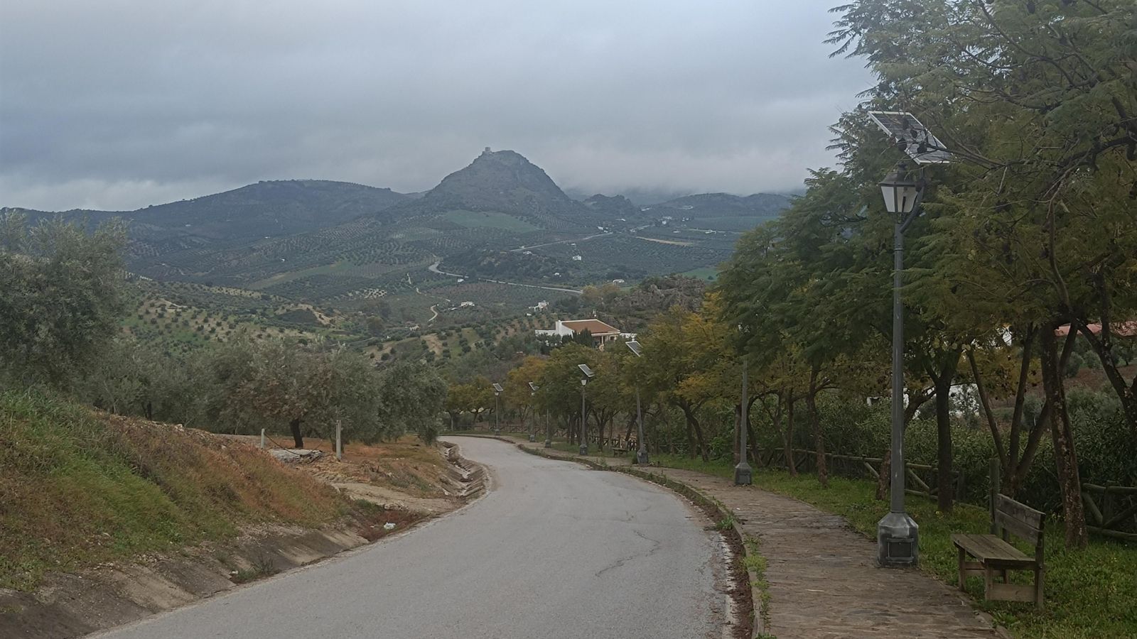 La calle de la Estación baja a la Vía Verde. Al fondo, vemos el Castillo del Hierro de Pruna sobre un peñón.
