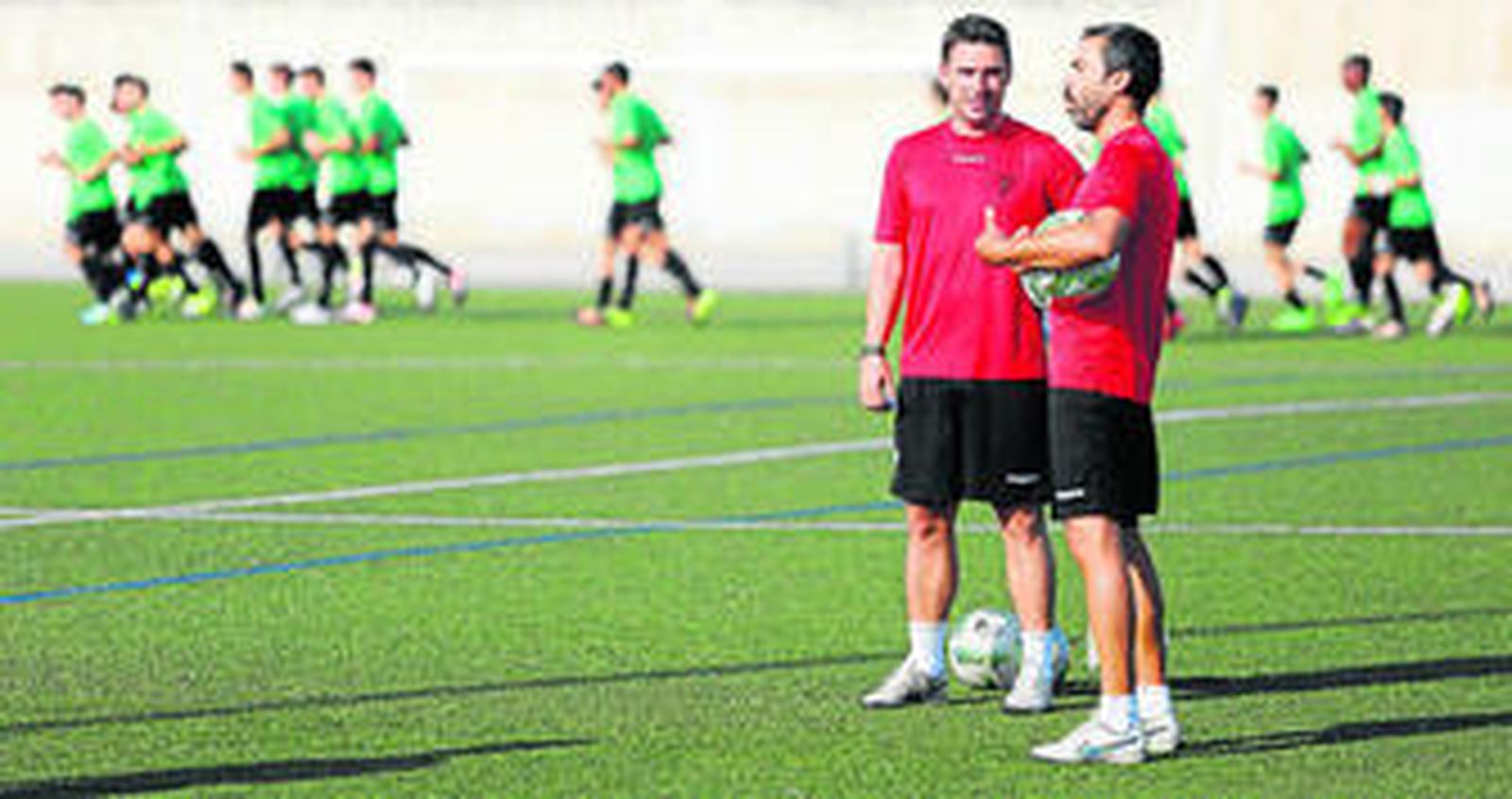 El técnico del filial blanquiverde, Luis Carrión, conversa con su segunda, Rafael Clavero, durante una sesión de entrenamiento de su equipo en las instalaciones de Miralbaida.