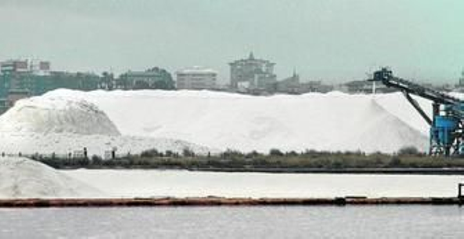 Montaña de sal donde deposita Salinas del Odiel su producción, con la ciudad de Huelva al fondo.