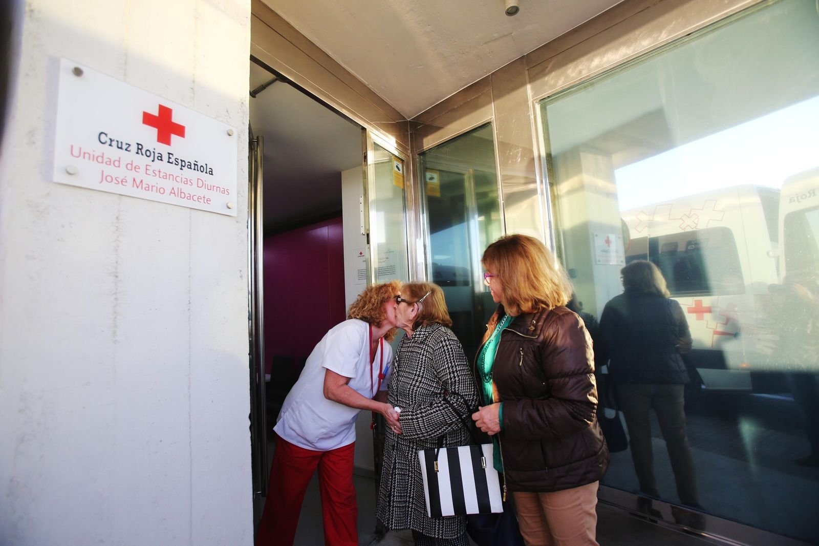 Una usuaria se despide hasta mañana de una trabajadora, ante un familiar que llega a recogerla.