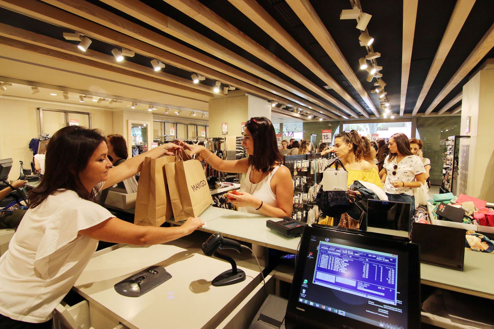 La empleada de una tienda entrega unas bolsas a una joven.