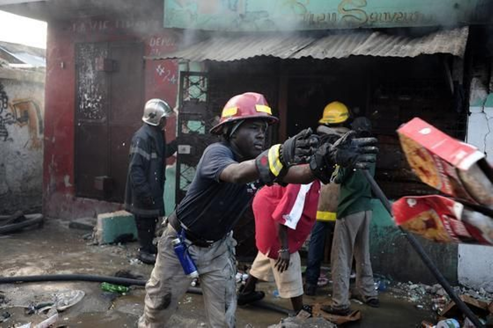 Un bombero trata de sofocar un fuego, mientras otro recoge alimentos.

Foto: Agencias