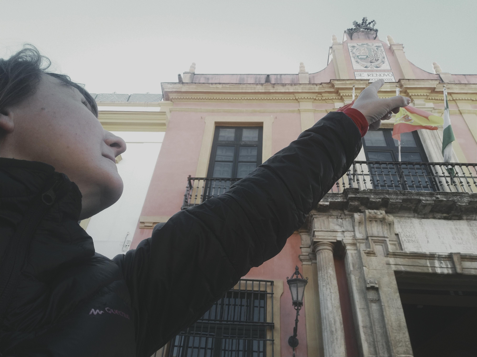 Guía de la ruta señalando el escudo de Felipe V en el Patio de Banderas.