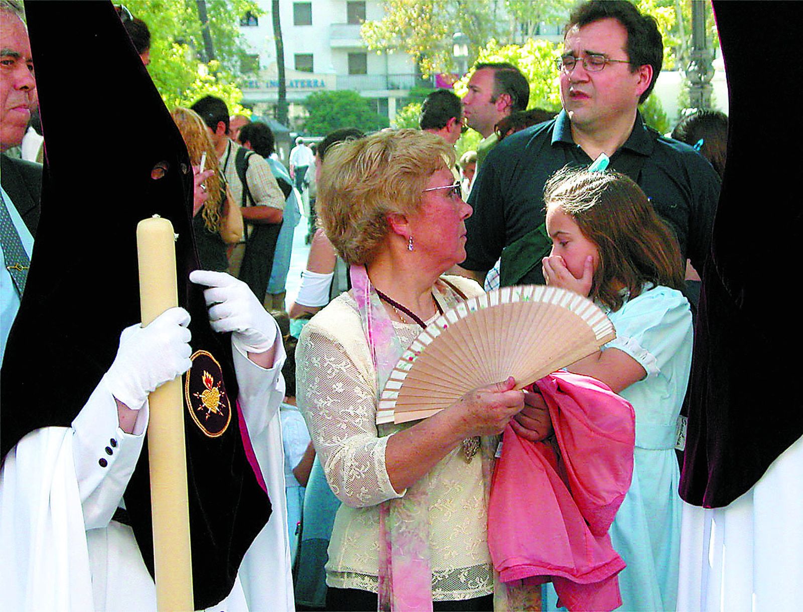 Una devota se abanica viendo el discurrir de una cofradía.