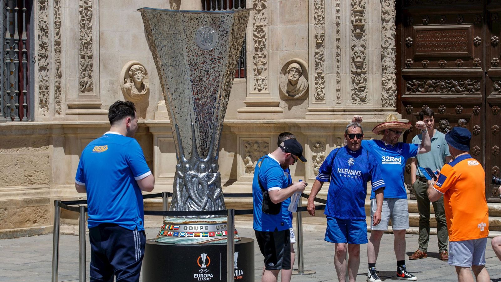 Aficionados escoceses del Glasgow Rangers se hacen fotos con una copa de la UEFA gigante colocada en el Ayuntamiento, en la previa de la final de 2022.