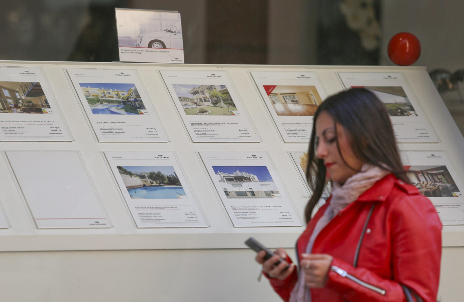 Una mujer pasa junto al escaparate de una inmobiliaria.