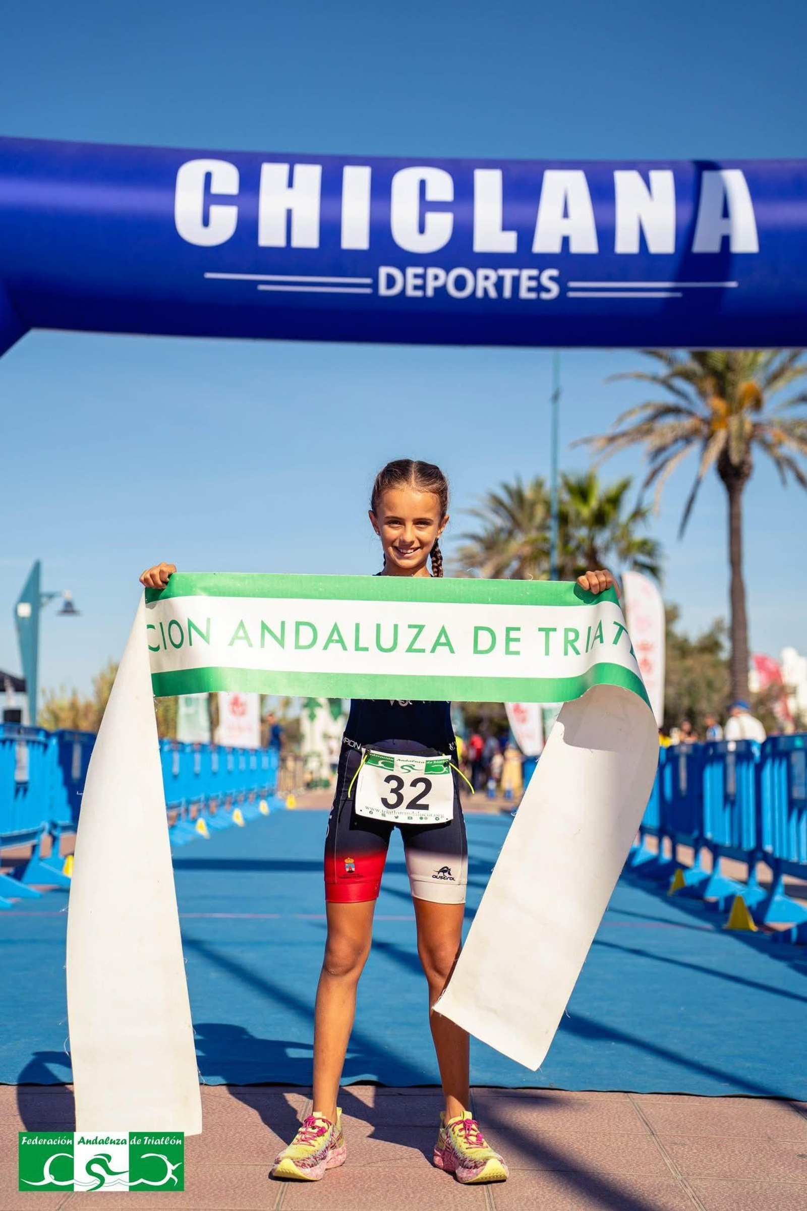 Claudia Peña sostiene la cinta de la línea de meta después de proclamarse campeona de Andalucía.