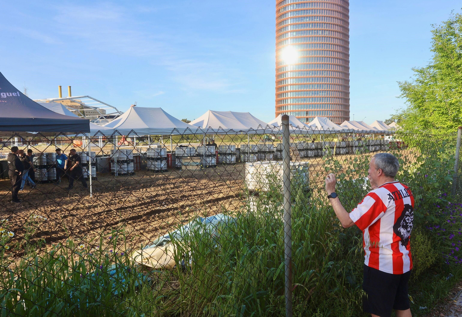 Un aficionado del Athletic observa el montaje de la gran barra de la fan zone de su equipo.