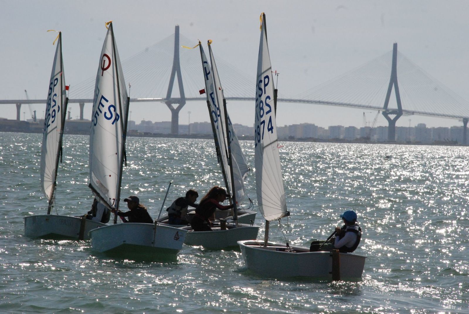 Regatistas compiten con el Puente de la Constitución de 1812 al fondo.