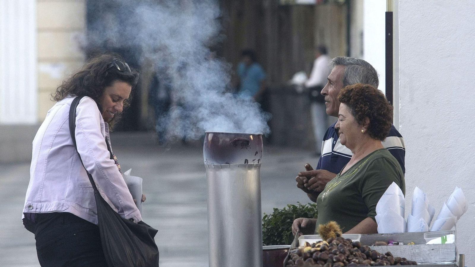 Una clienta, en la Plaza Alta de Algeciras, busca en su bolso el euro que cuesta un paquete de castañas asadas.