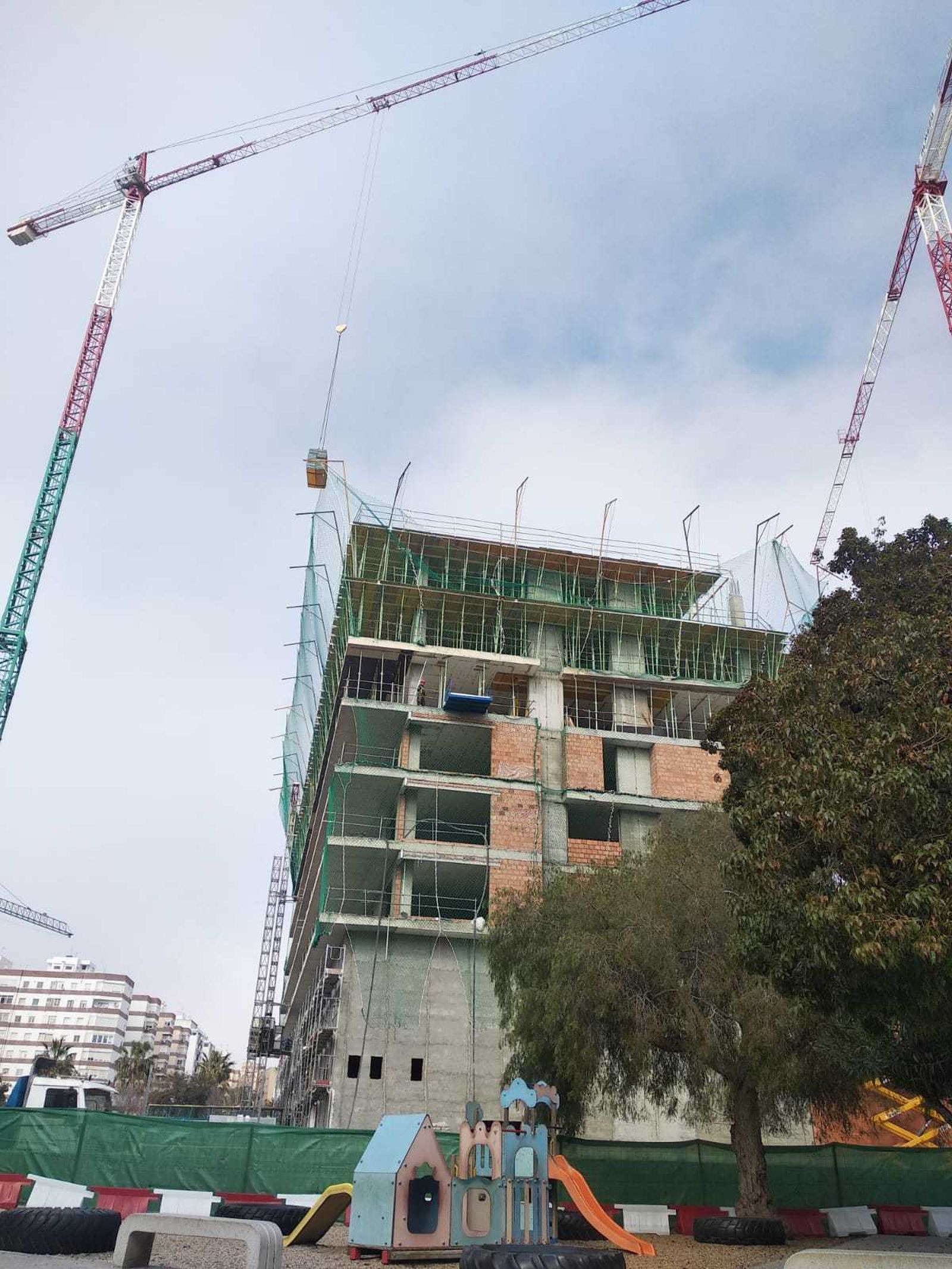 Patio del CEIP Mar Mediterráneo con el edificio en construcción detrás y las grúas que tienen actividad en la obra