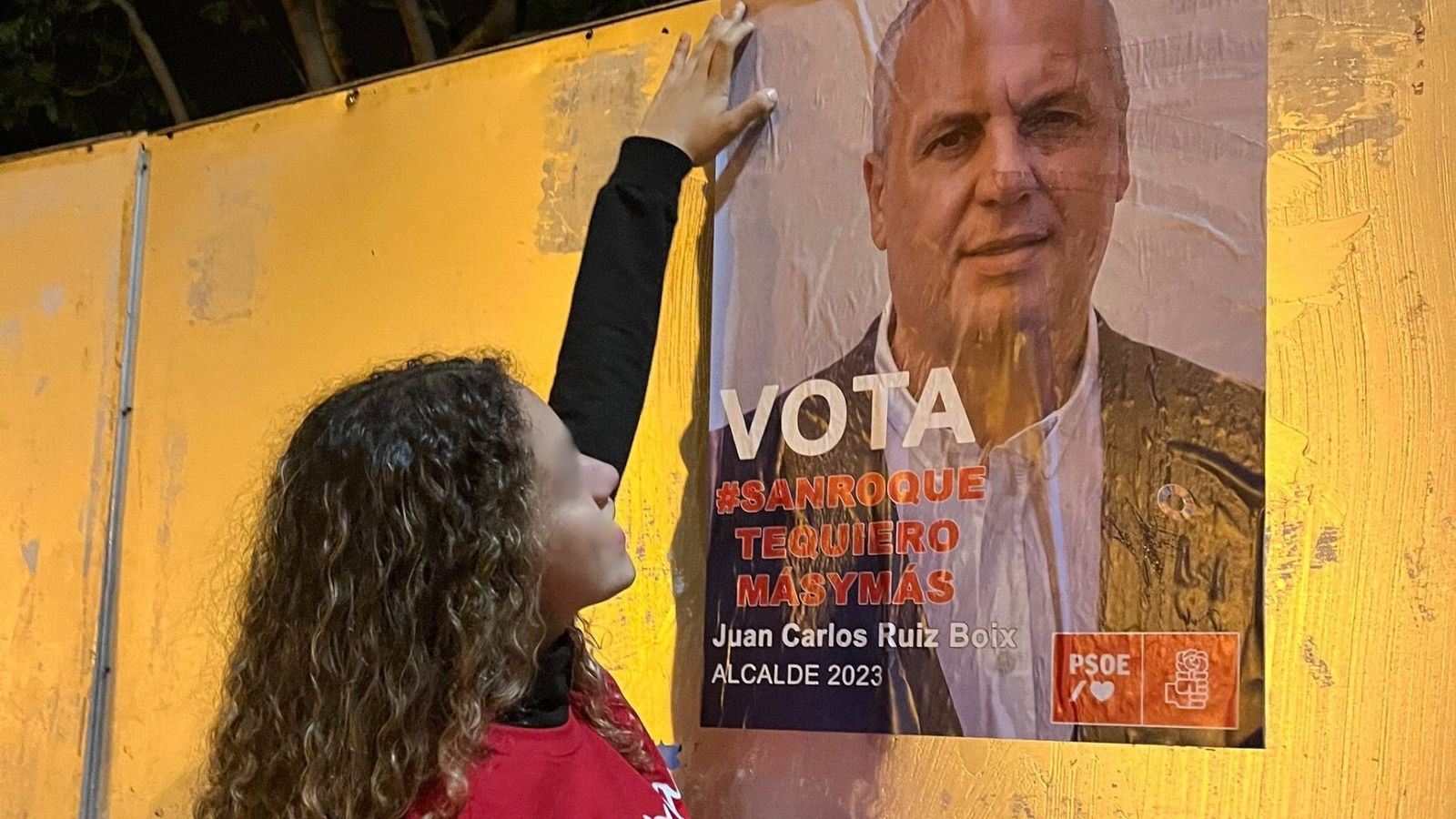 Irene Ruiz Domínguez, cuelga un cartel con la foto de su padre, Juan Carlos Ruiz Boix, alcalde de San Roque, durante las pasadas elecciones municipales de 2023.