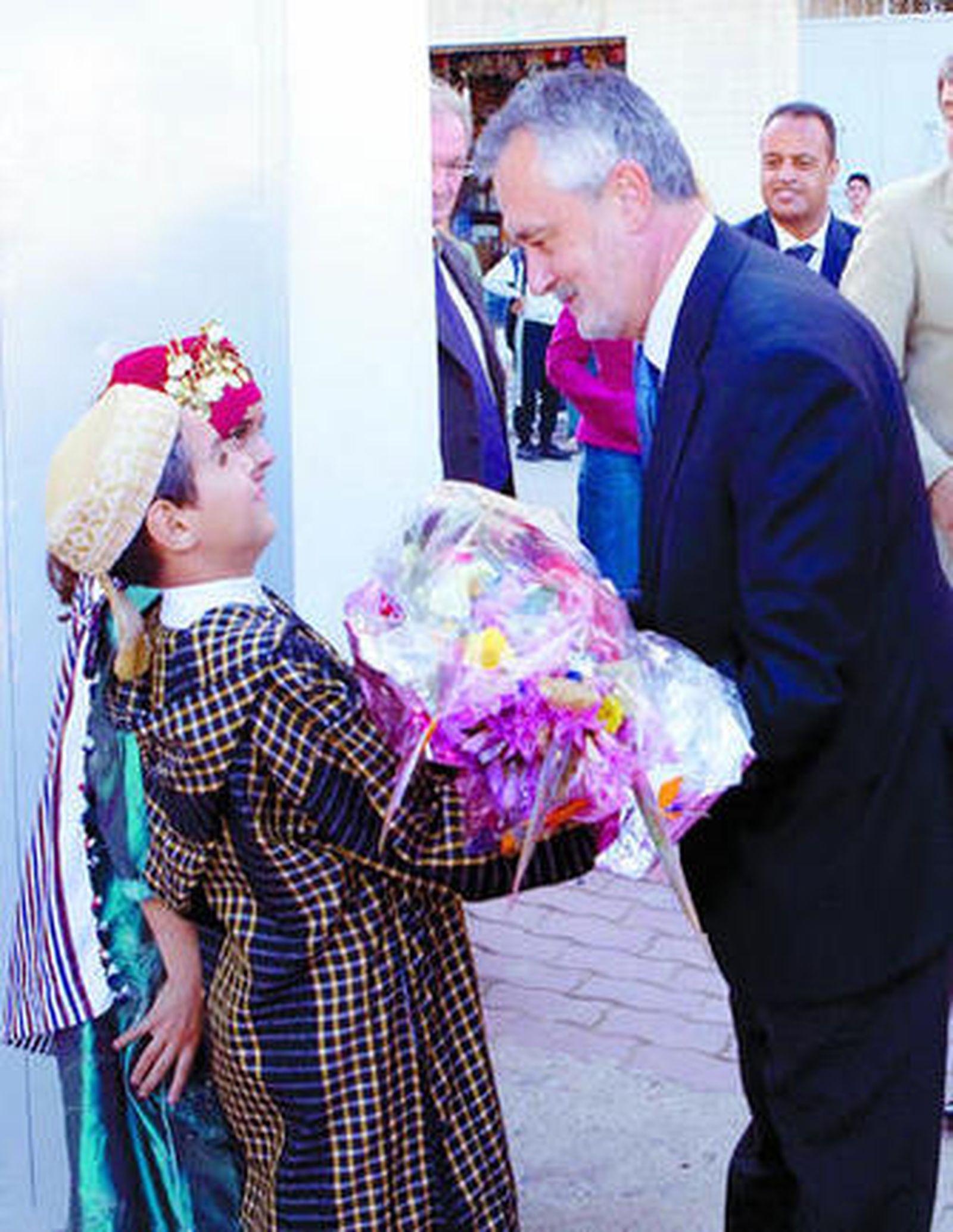 Dos niños marroquíes ofrecen un ramo de flores a Griñán.