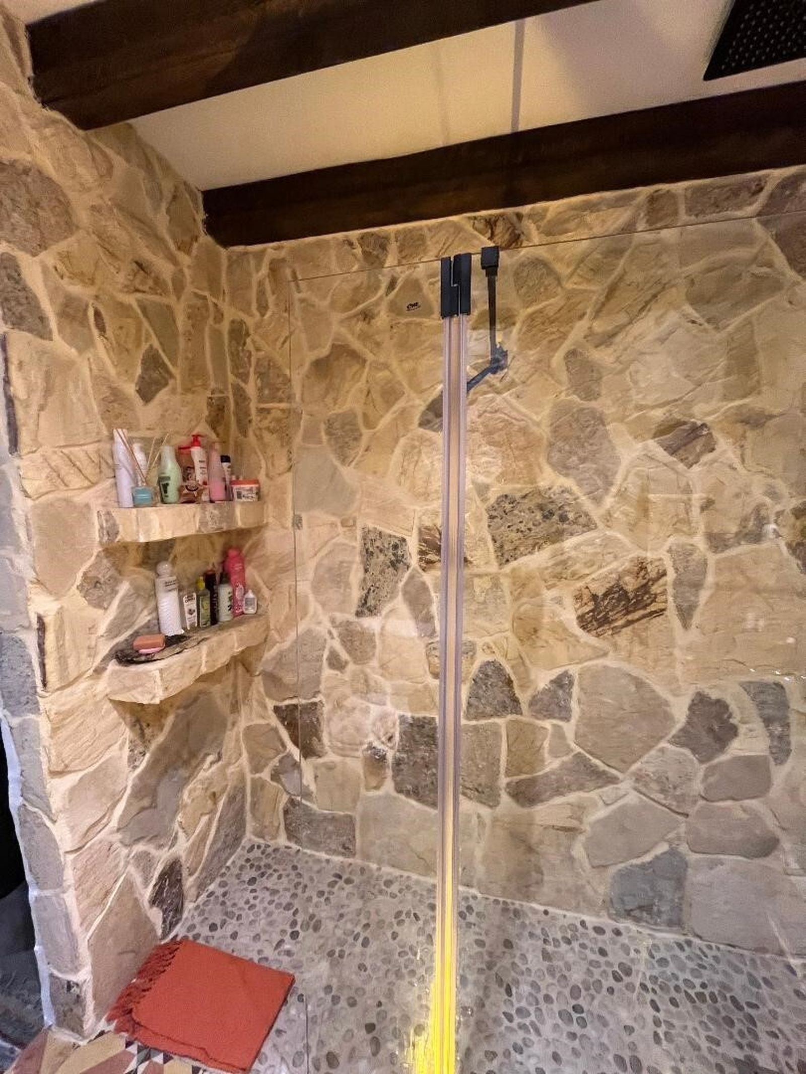 Las paredes de la ducha, con chorro en cascada son de piedra de Tarifa.