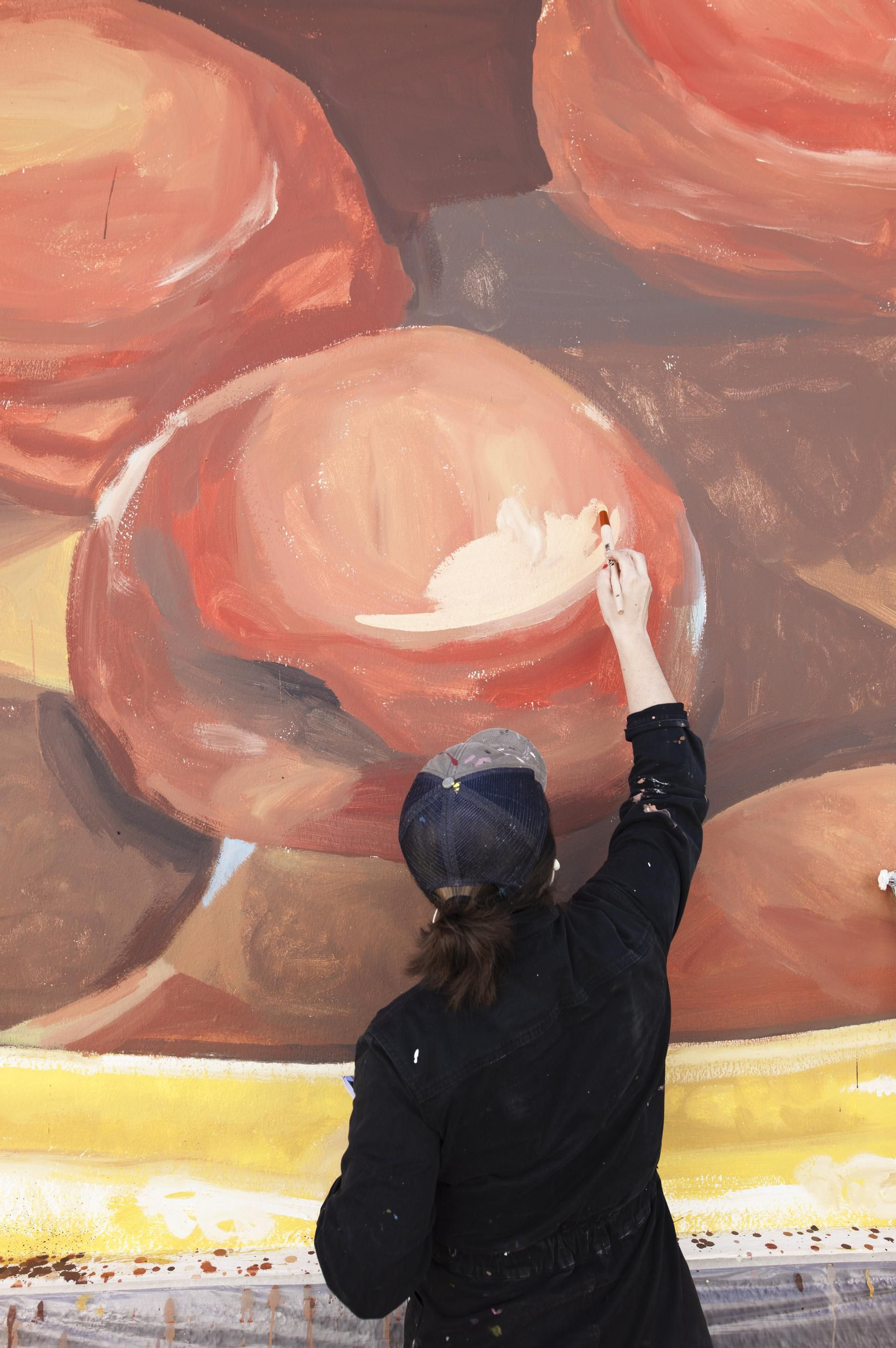 La autora, Virginia Bersabé, pintando una zona del mural.