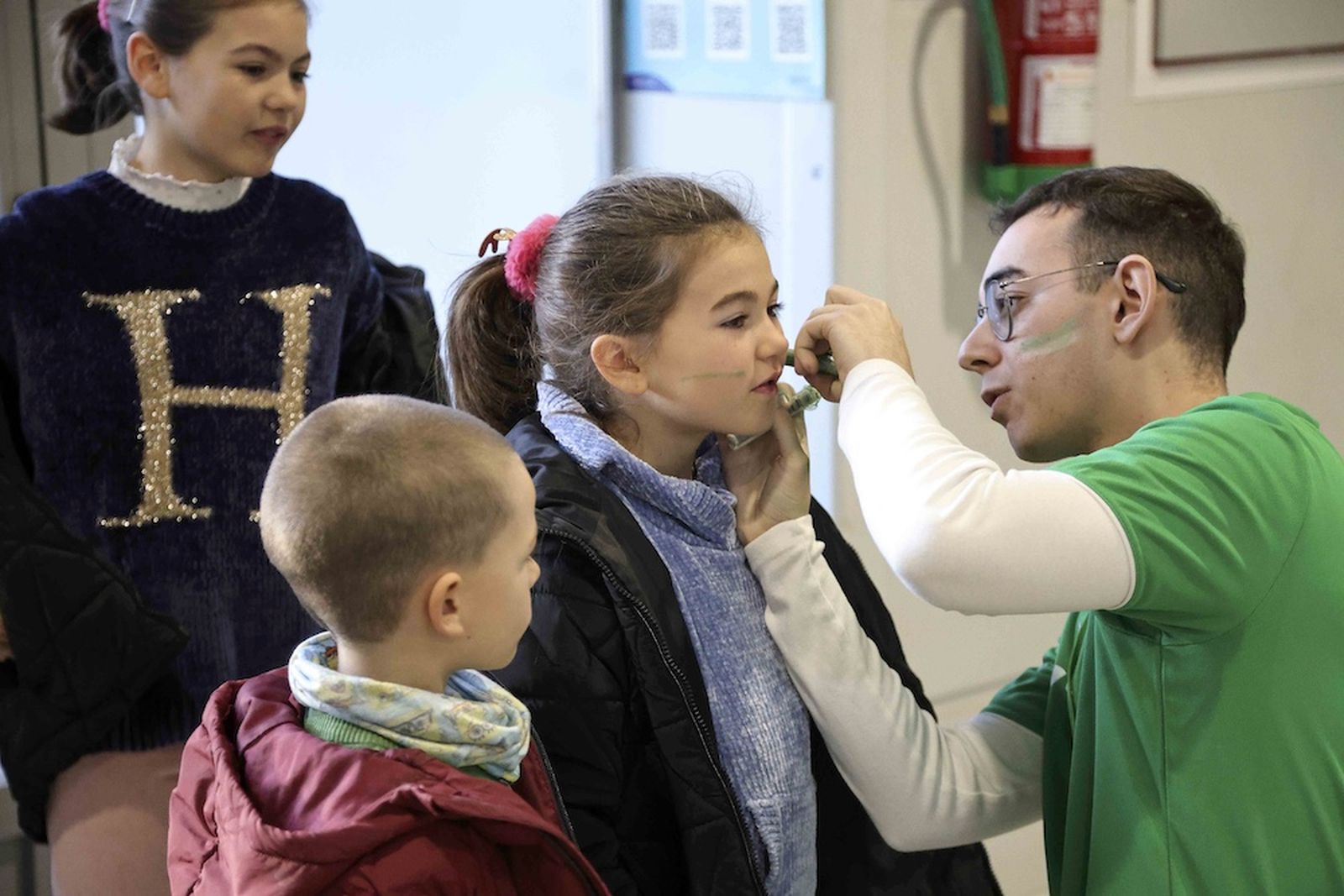 Una niña se pinta la cara con los colores verdes a la entrada en un partido de Unicaja en el Moisés Ruiz.