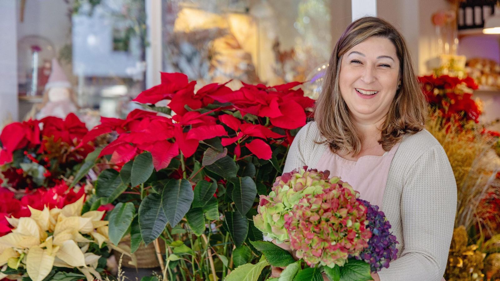 Adelina Fernández posa con las flores de Pascua detrás.