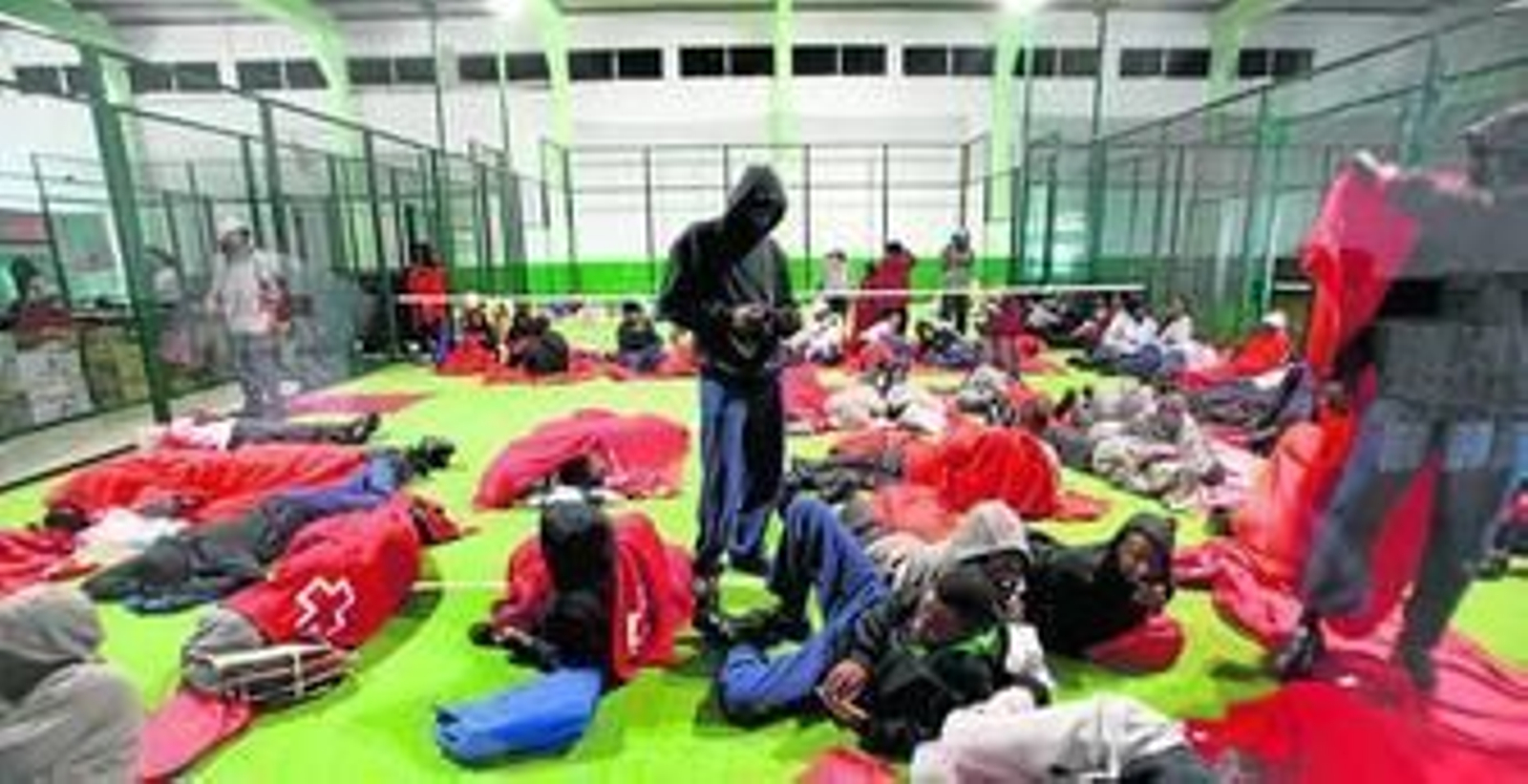 Un grupo de inmigrantes descansa en el interior de una pista de pádel del polideportivo de Tarifa, el pasado 12 de agosto.