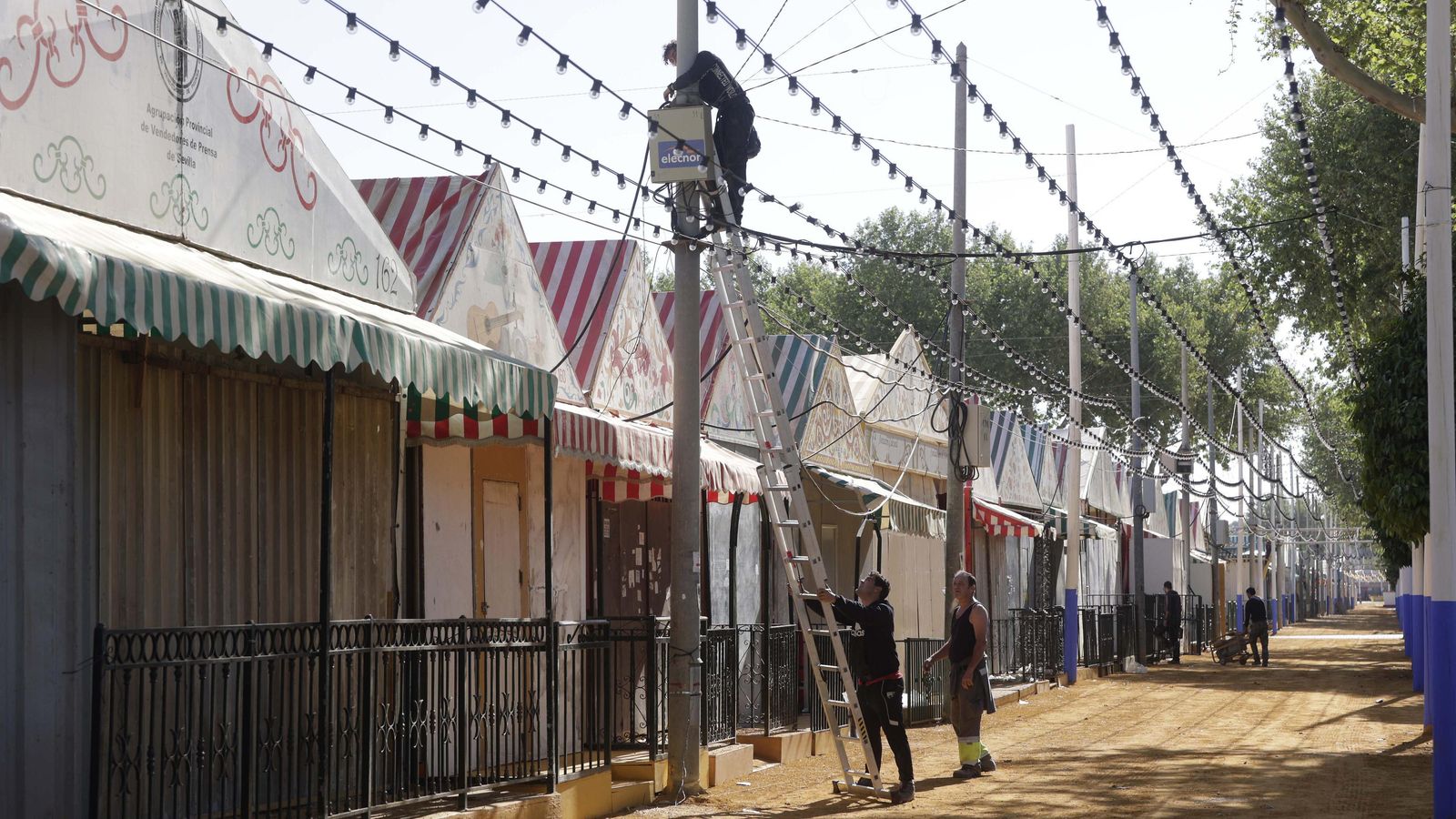Operarios colocando un cuadro de luz del alumbrado del real de Los Remedios.