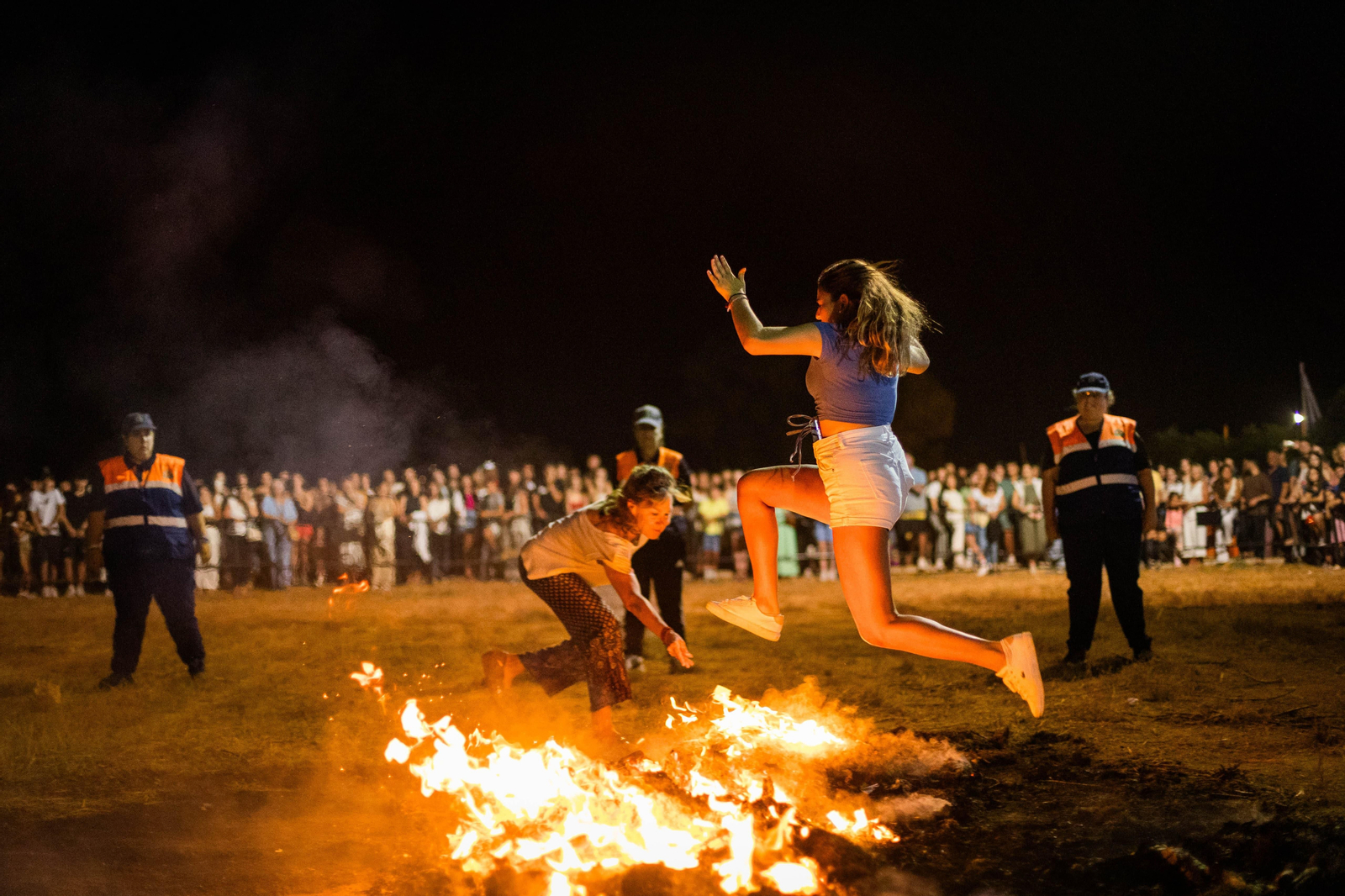 Una joven salta sobre la hoguera de San Juan en la playa de La Casería, en San Fernando